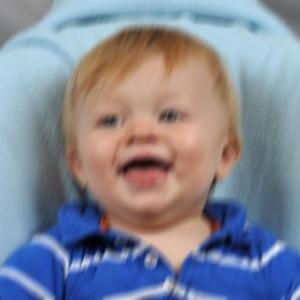 The child's face should be in focus and not blurry. Select a shorter exposure time or use a tripod or place camera on a steady surface to eliminate camera movement.