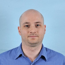 Foto de un hombre frente a un fondo azul. 